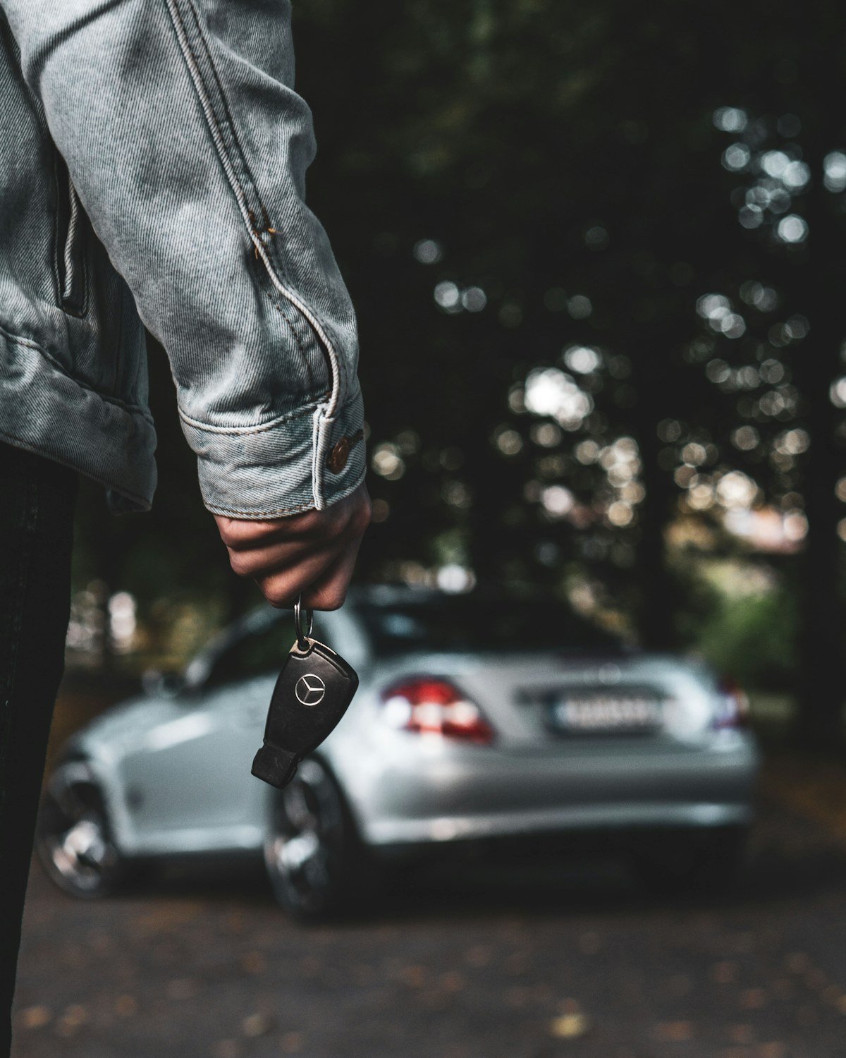 Žmogus su rakteliu šalia stovinčio automobilio